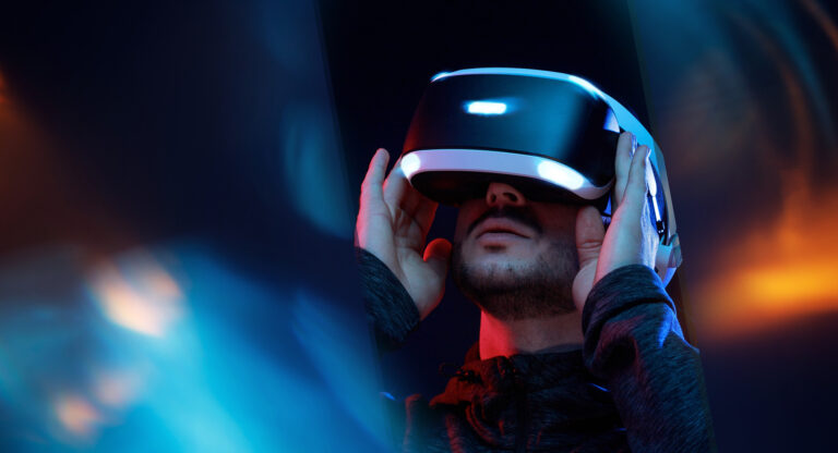 Man in a dark room touching the AR/VR glasses on his face, demonstrating the use of nanoelectronics in consumer electronics.